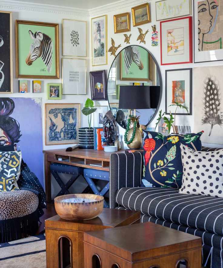 A blue maximalist living room with a gallery wall and circular wall-mounted mirror