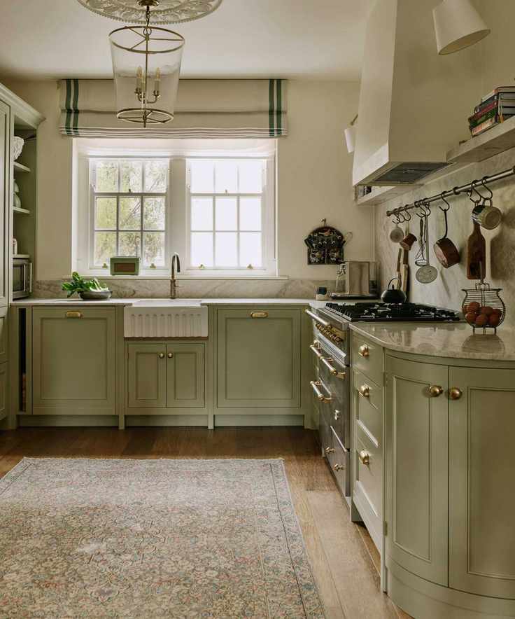 a traditional shaker kitchen in a london home painted in a soft green hue with a fluted sink, vintage rug, plaster cooker hood and rangecooker
