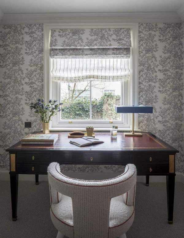 desk in front of a window with roman blinds, lamp and stationery