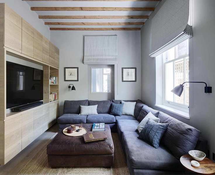 Small living room lighting ideas featuring black wall lamps above a large L-shaped blue sofa.