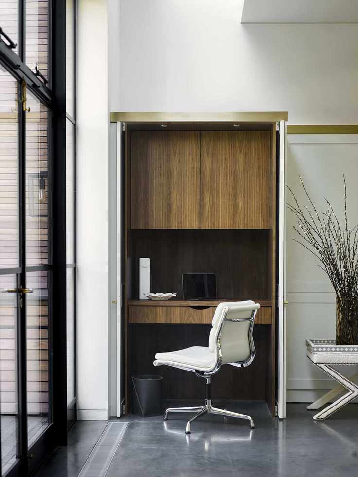 Built in desk and cabinetry in room with white walls and grey flooring