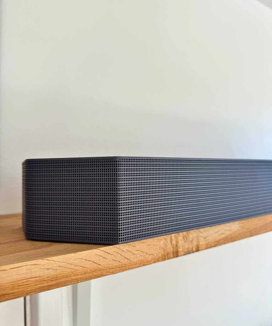 Samsung HW-Q990F soundbar on wooden shelf.