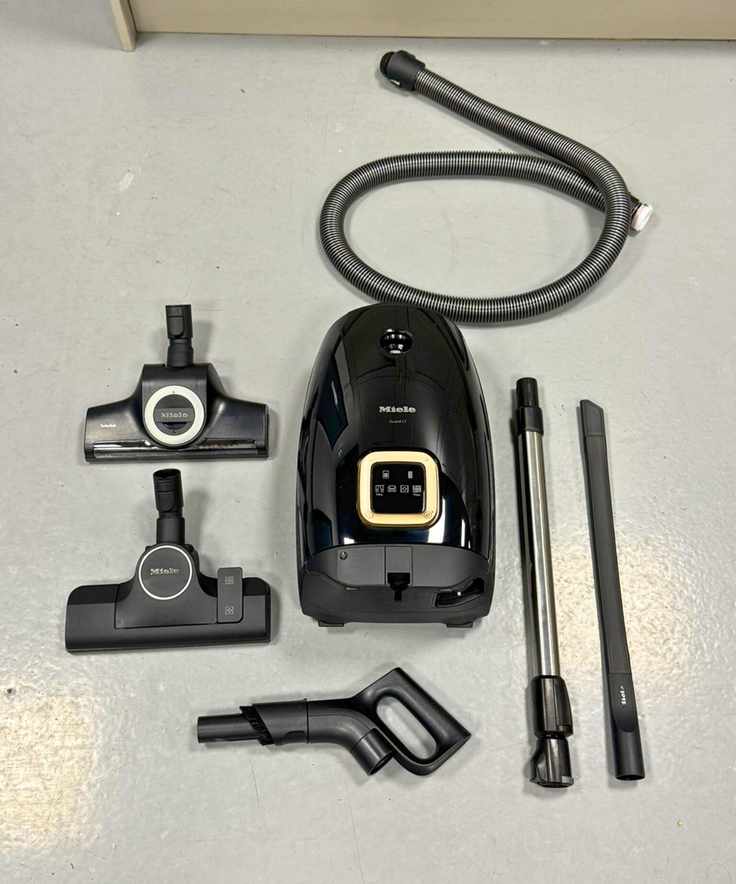 All parts and attachments of the Miele Guard L1 Cat and Dog canister vacuum on gray floor in the test center.