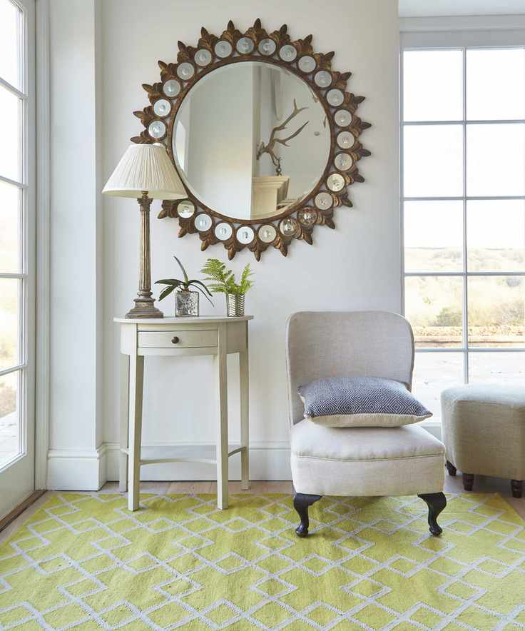 A living room featuring a large brass mirror and a yellow rug