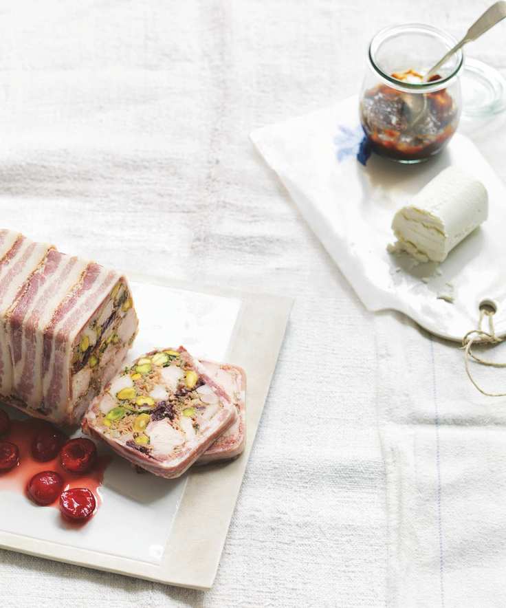 chicken and pistachio terrine with pickled cherries on a white board on a white tablecloth