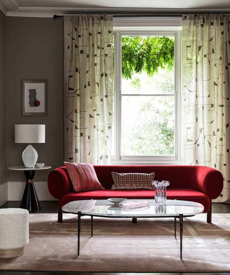 Monochrome living room with vibrant red velvet sofa and geometric curtains