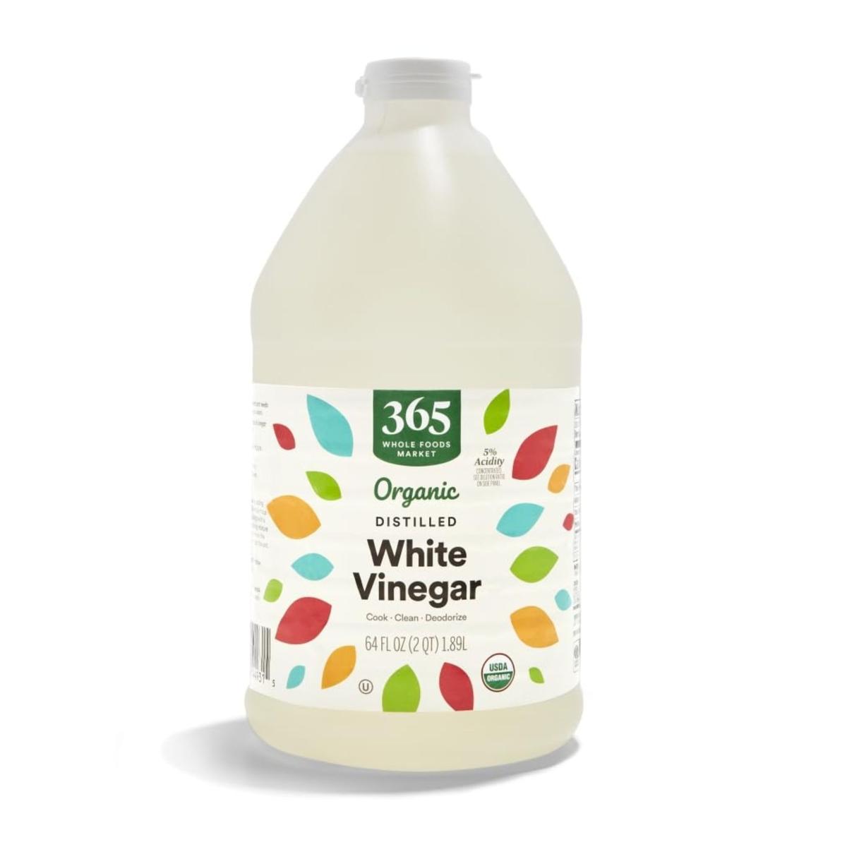 A clear plastic bottle of white vinegar with a white and colorful label