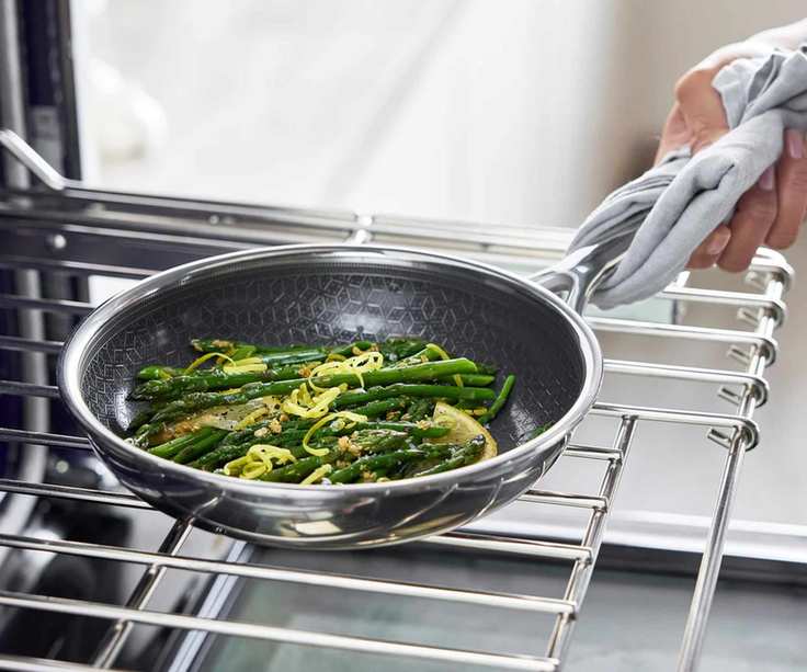 GreenPan Spectra Thermobond Frying Pan filled with asparagus being lifted from an oven rack.
