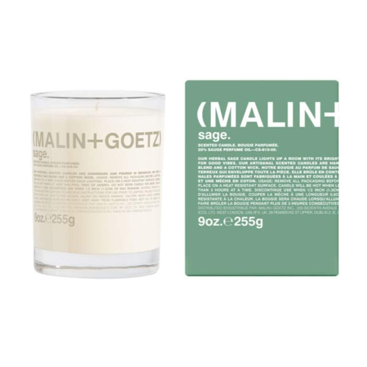 A white glass candle next to a green cardboard candle packaging box