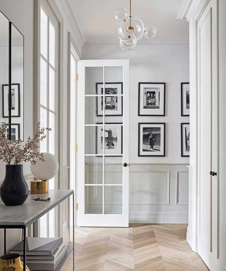 A modern hallway featuring French doors and a stylish chandelier