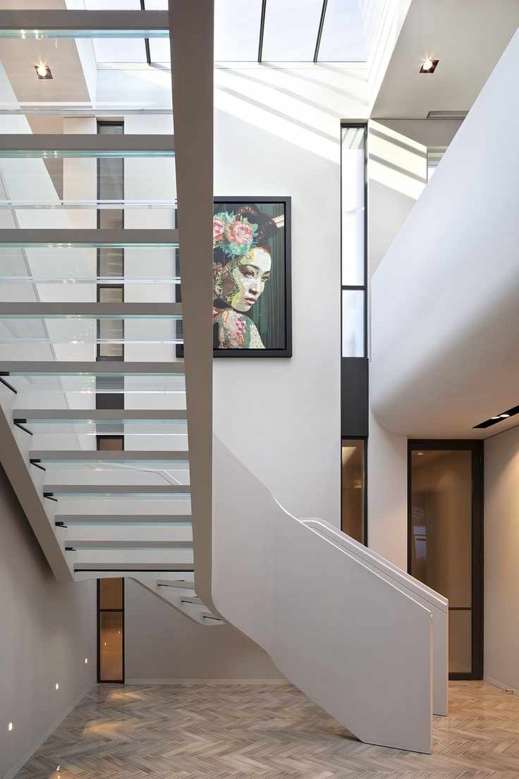 View of staircase with glass treads from underneath, parquet floor and neutral walls