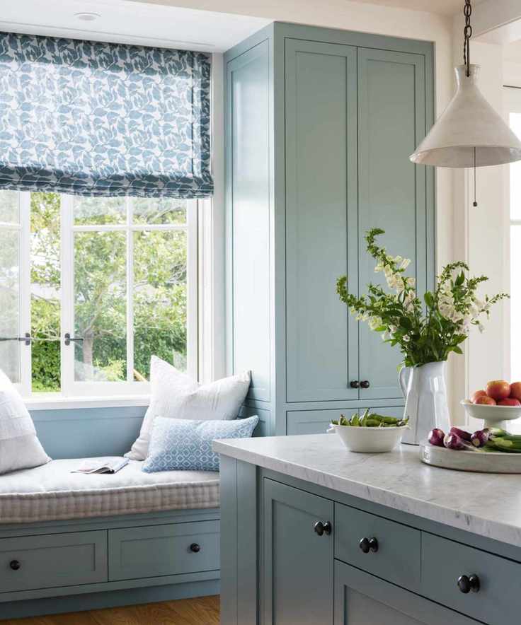 A midimalist kitchen featuring light blue cabinets and gingham-upholstered seating