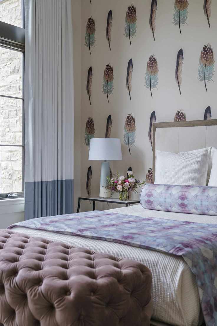 pink and gray bedroom with feather wallpaper, teen girl, button backed ottoman, gray and white drapes, side table, table lamp