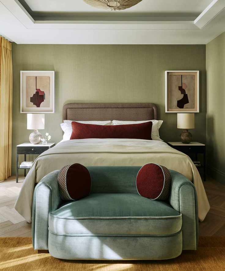 A cozy modern bedroom with a small blue velvet couch at the foot of the bed