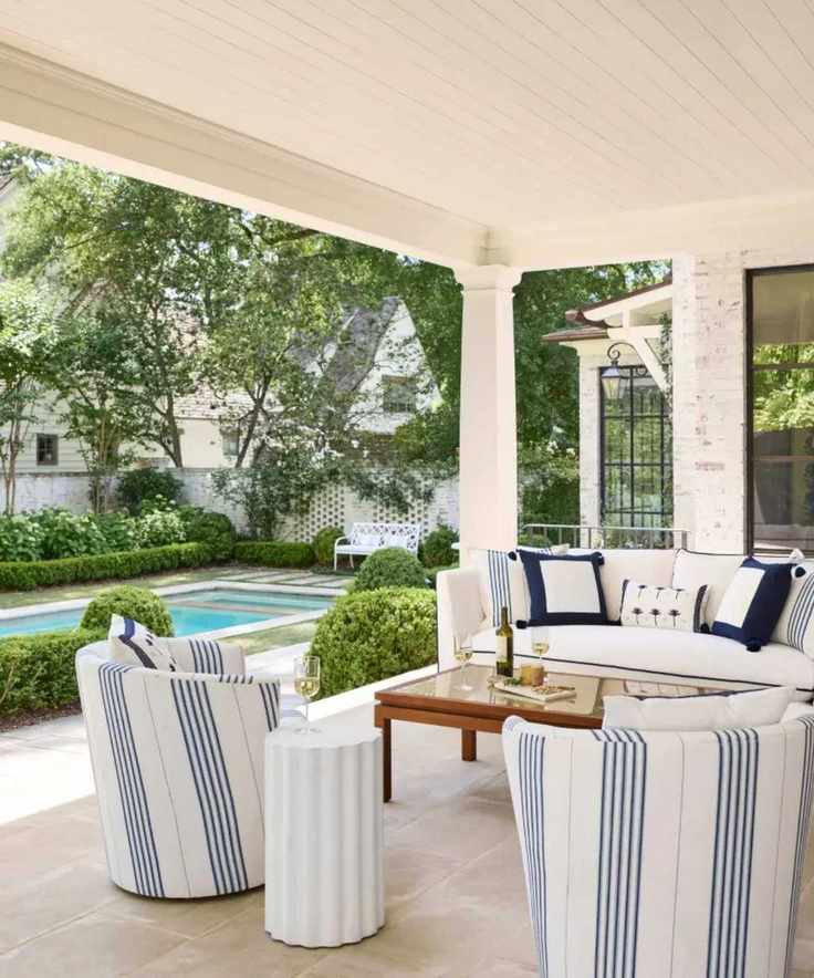 hamptons outdoor patio outdoor living room next to a pool with blue and white coastal furniture