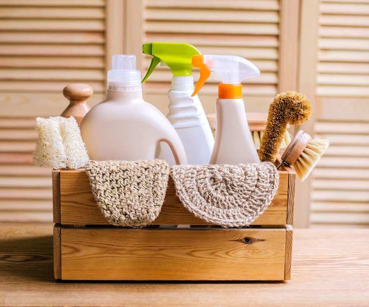 A wooden crate filled with non-branded cleaning spray bottles