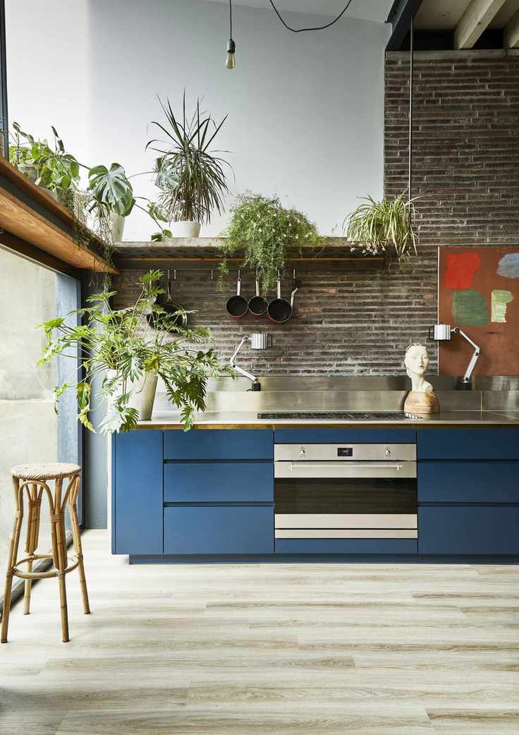 Blue kitchen ideas featuring mid blue painted base cabinets with chrome backsplash and fittings, in a large warehouse-style room with exposed brick walls.