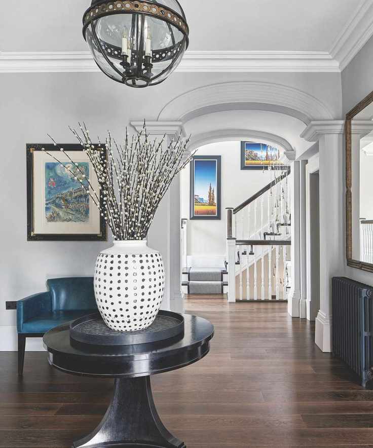 A bright entryway with a circular table and colorful artwork on the walls.