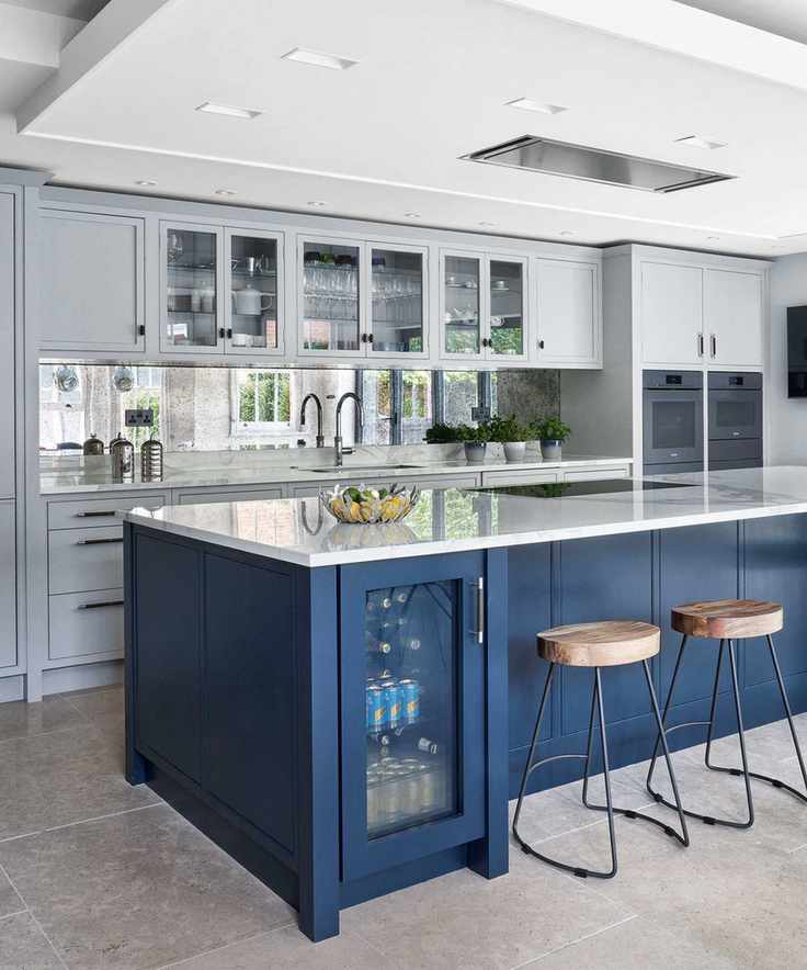 Kitchen featuring a dark blue island and mirror tiled wall