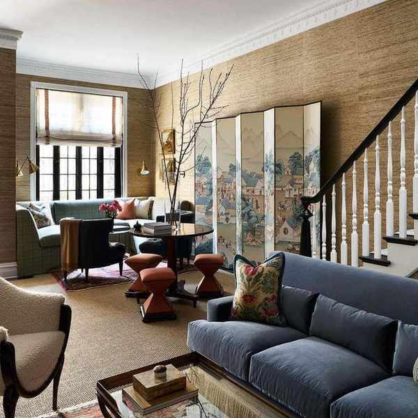 an open concept room with different sitting areas, textured walls, a decorative partition, and an overall warm neutral color scheme