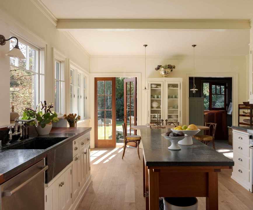 vintage style kitchen with dark island and white cabinets and wooden floors