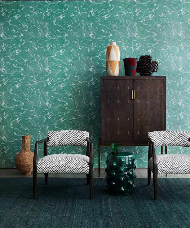 Living room picture showing deep green wallpaper with patterned chairs in front.