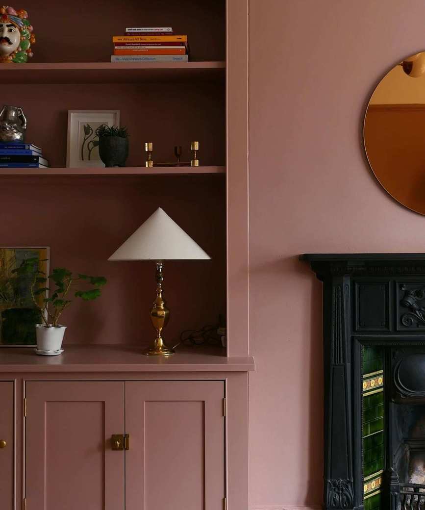 Pink shelves in living room with fireplace, lamp and objects