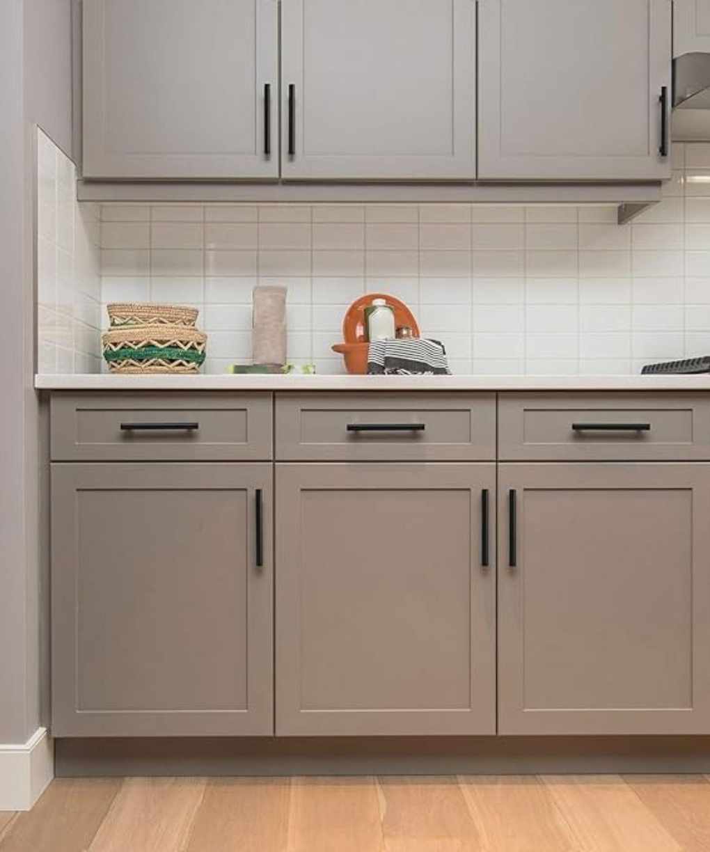 Gray kitchen cabinets with matte black hardware and white countertops