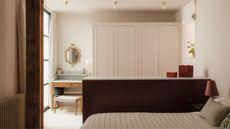 Romantic style bedroom with pale pink walls, vanity area with mirror, built-in cupboards, burgundy painted drawers that separate the bed