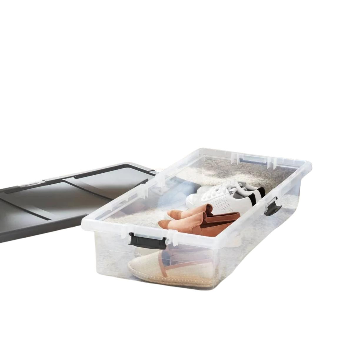 A clear under-bed storage box with shoes inside of it