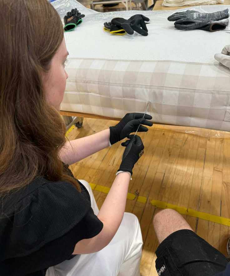 Emilia stitching a side of a Hästens mattress.