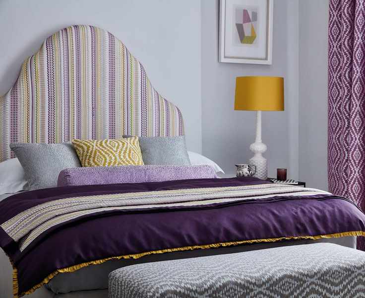 Lilac painted bedroom with large bedside table and purple curtains