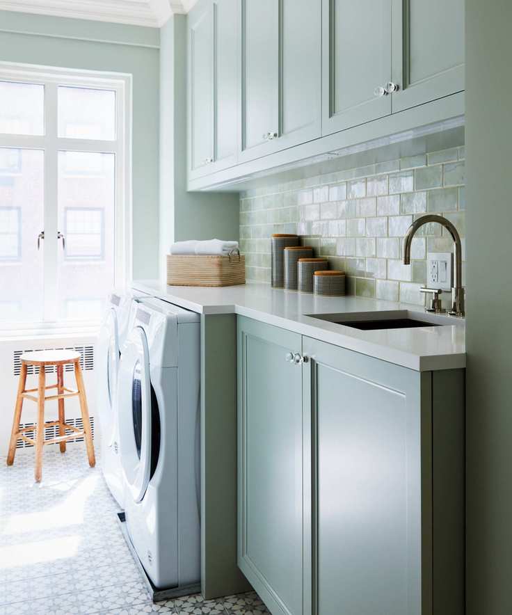 Laundry room featuring mint green cabinets and a stylish backsplash.