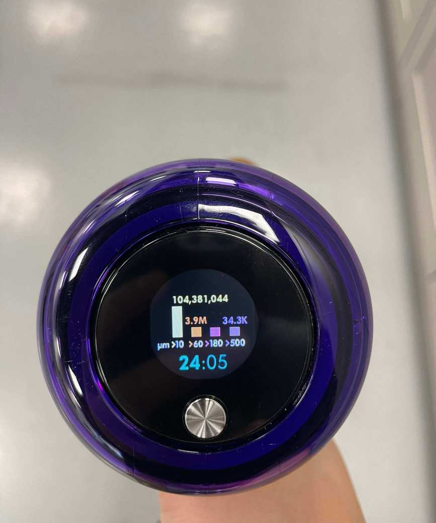 Close up of the Dyson V15 Detect screen showing data on particles vacuumed