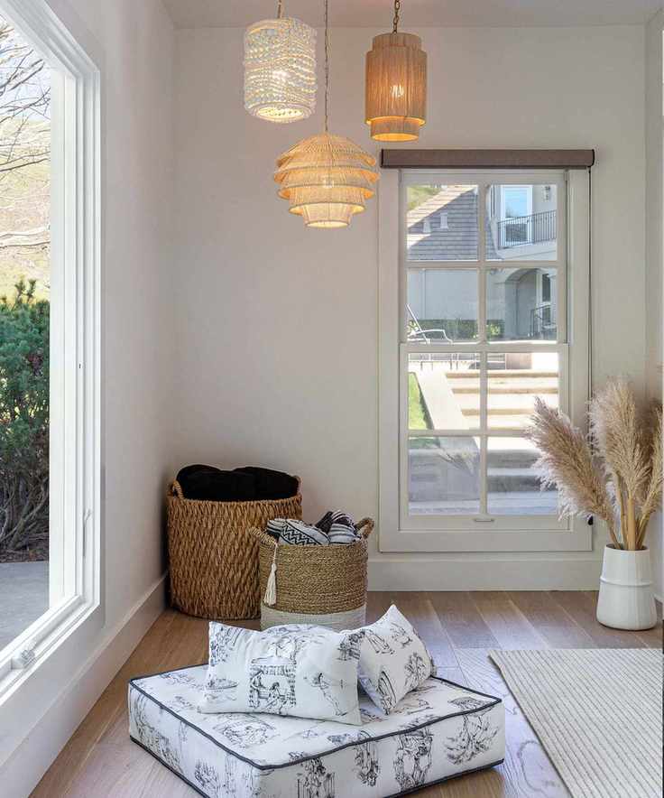Corner of cozy family room, cream painted walls, floor cushions, trio of pendants