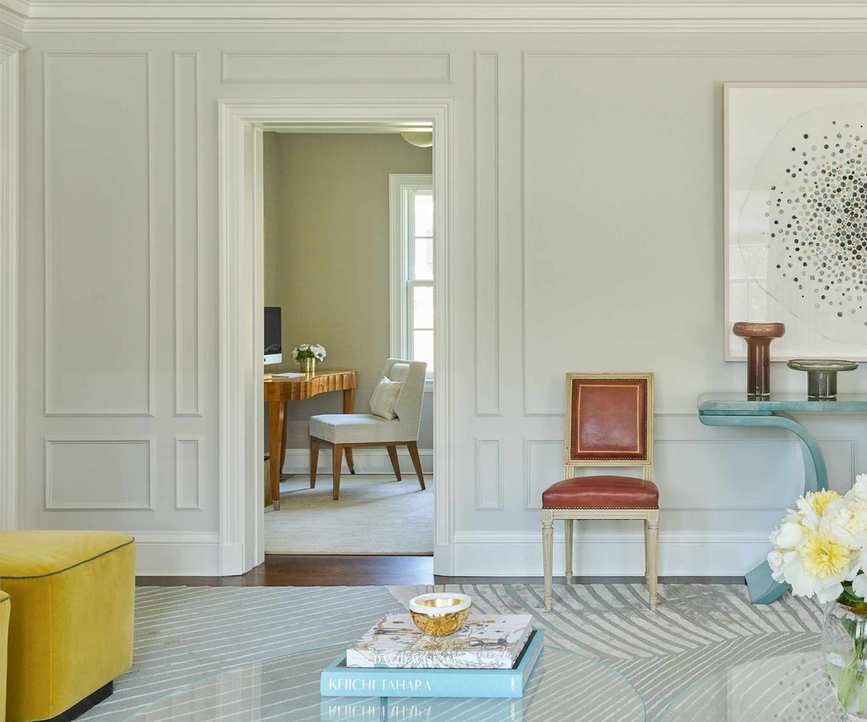 white walls with paneling and red louis XVI chair with modern furniture