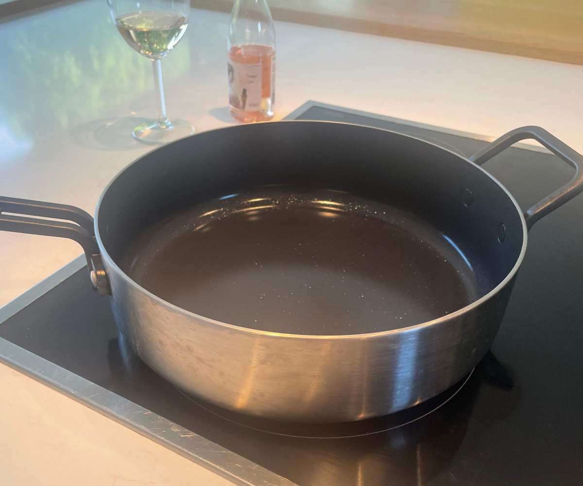 The Stanley Pan on my induction stovetop, next to a glass of rosé wine