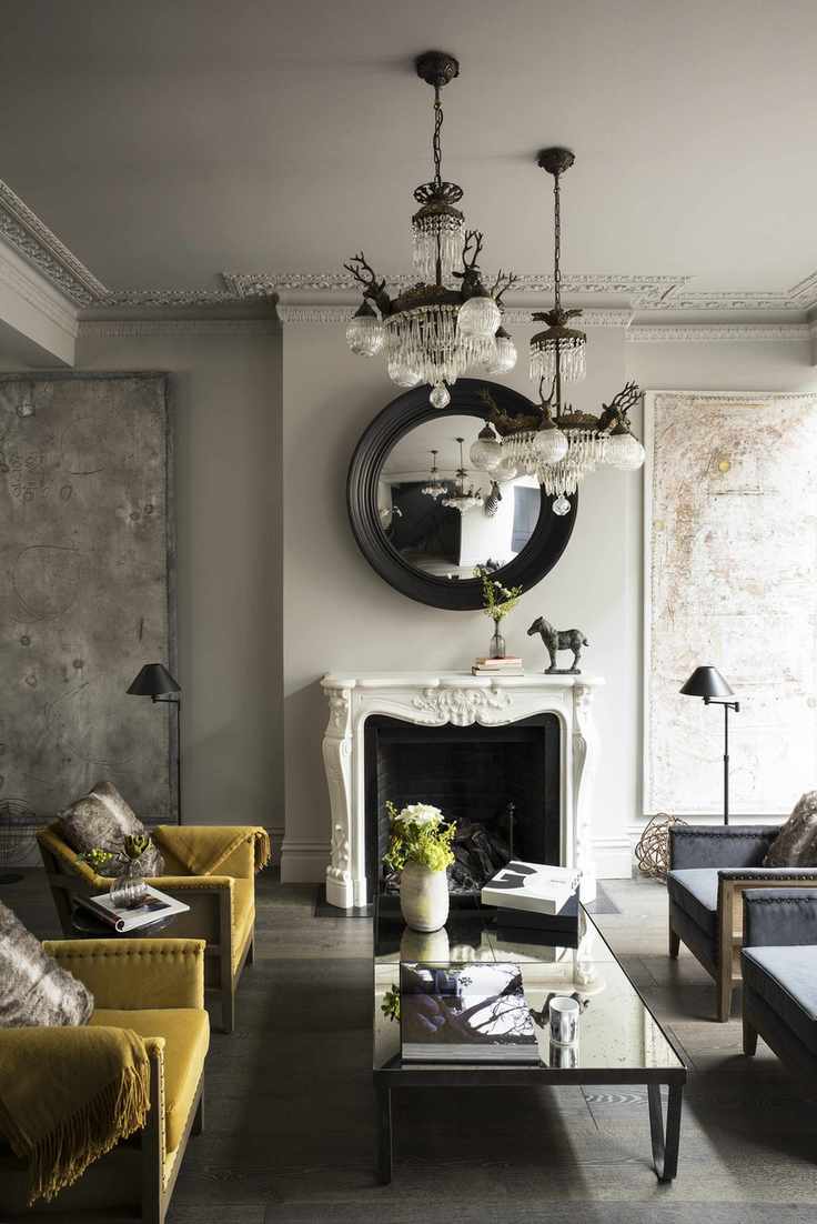 A yellow living room adorned with velvet chairs and a large white fireplace