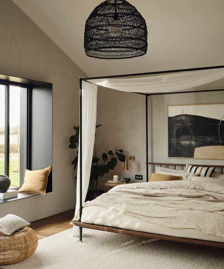 A neutral bedroom with a black four-poster bed