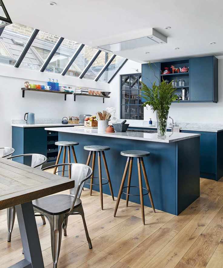 Open plan kitchen diner with blue cabinetry and wood flooring