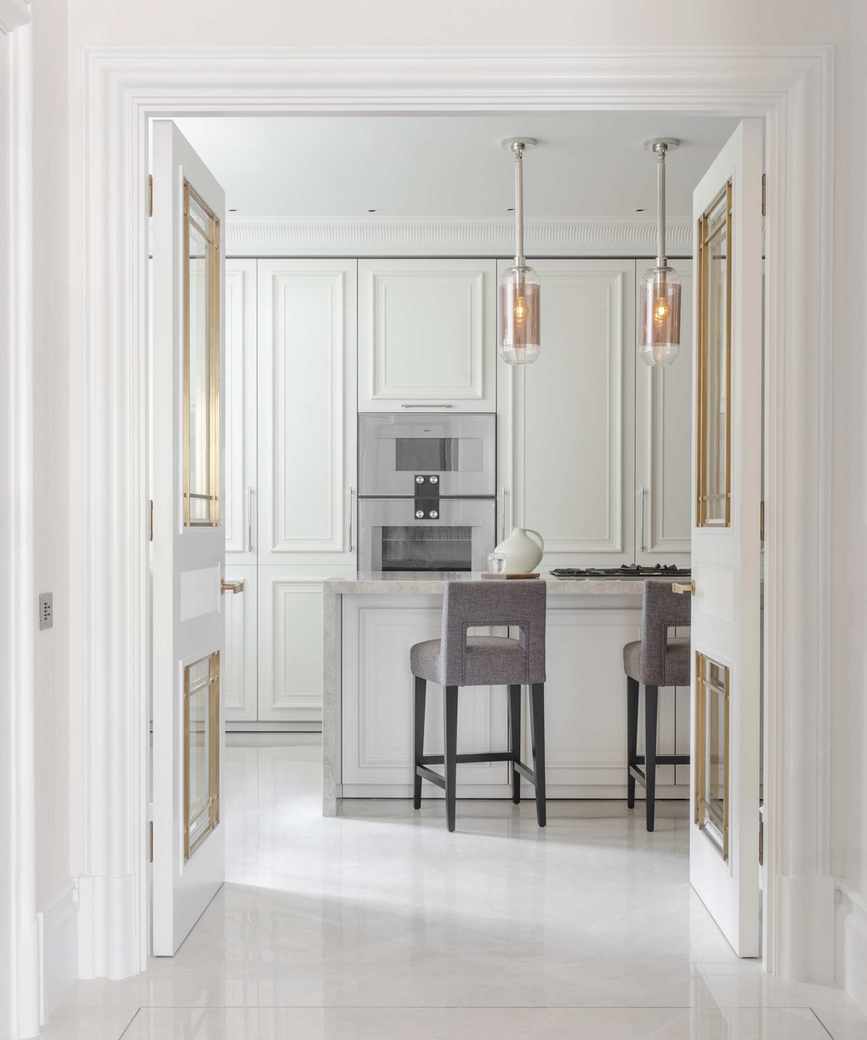 Chic white kitchen with a polished stone floor and visible island