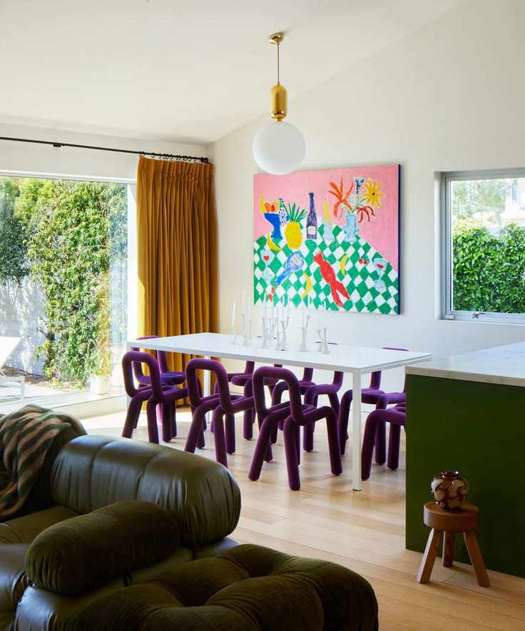 open plan living dining kitchen area with purple dining chairs and a green kitchen and couch
