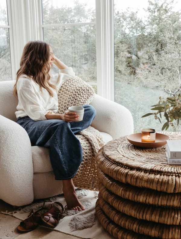 Camille Styles drinking coffee in bedroom armchair.