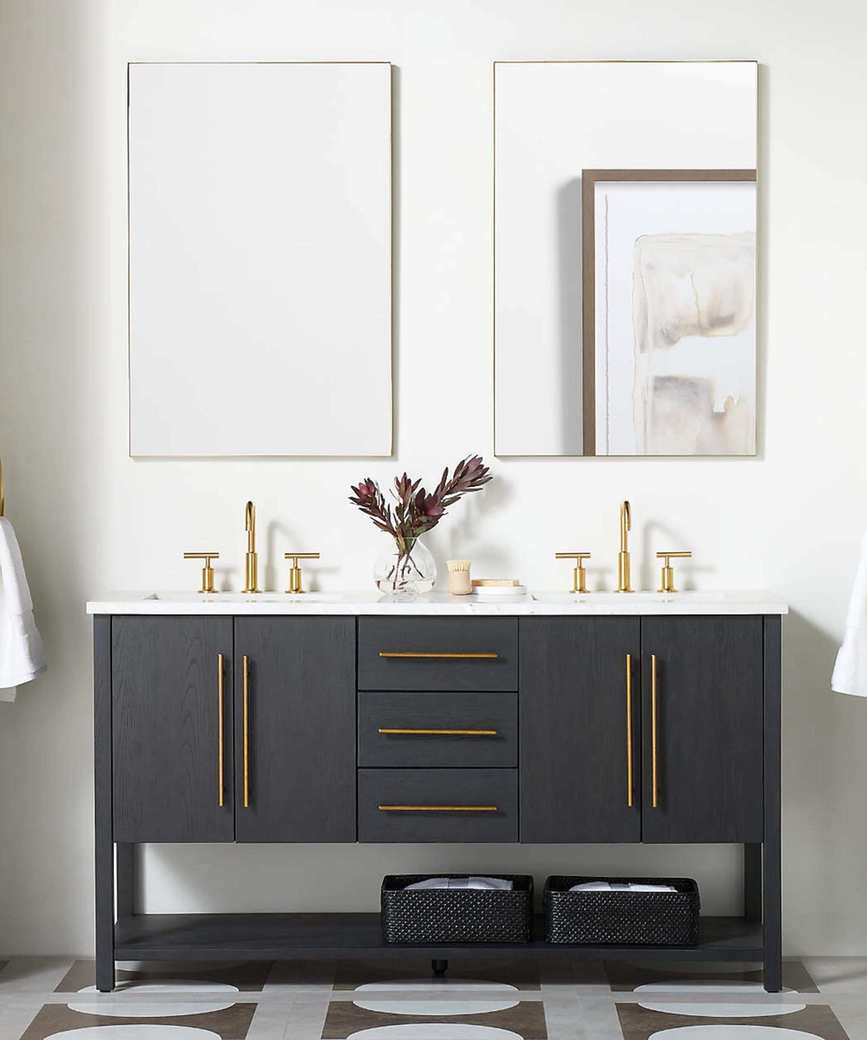 A white bathroom with two navy blue vanities and brass hardware