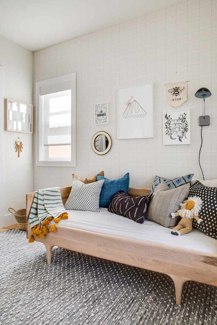 playroom with day bed, cushions and toys, gray rug, artwork on walls, tiled style wallpaper