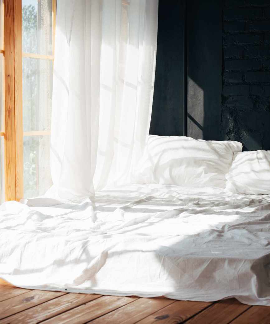 Bedroom, bed with white sheets next to open window on a sunny day