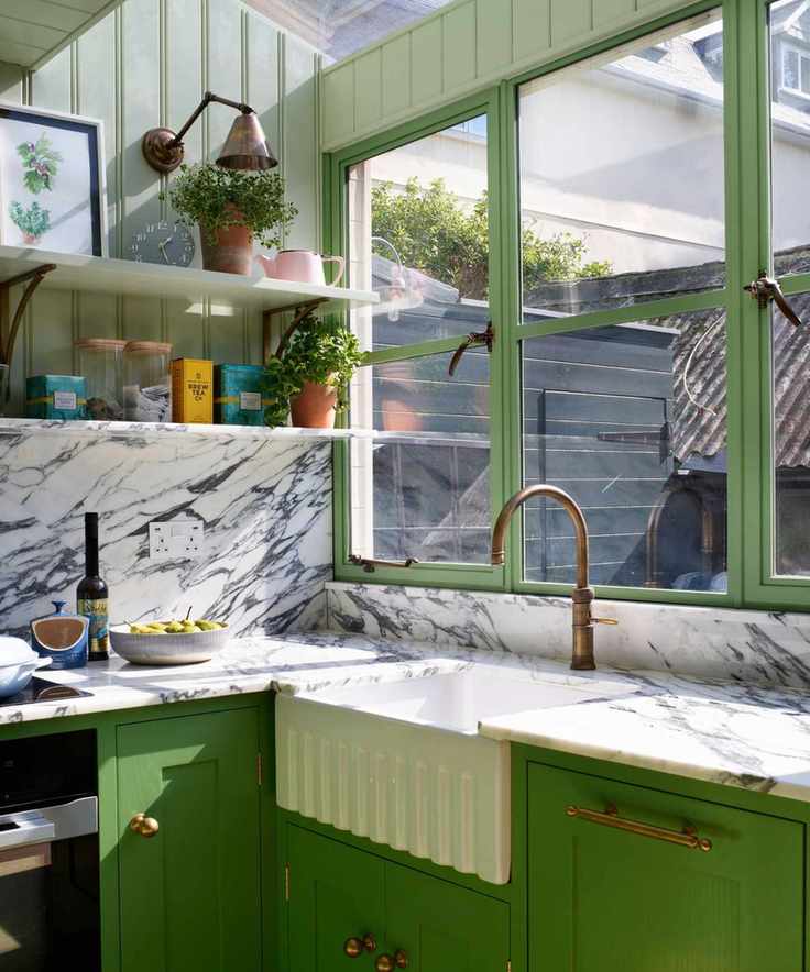a small U-Shaped kitchen with bright green cabinets, marble countertops, and soft green shelving