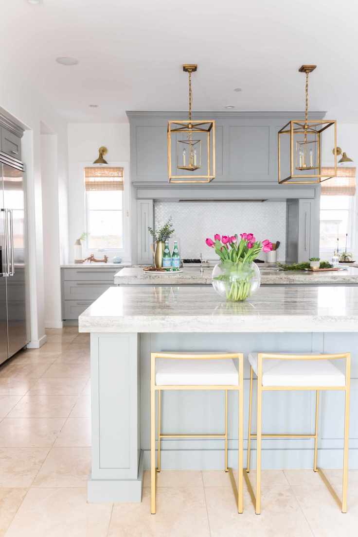 blue kitchen with 2 kitchen islands, gold stools and lantern pendants, stone floor