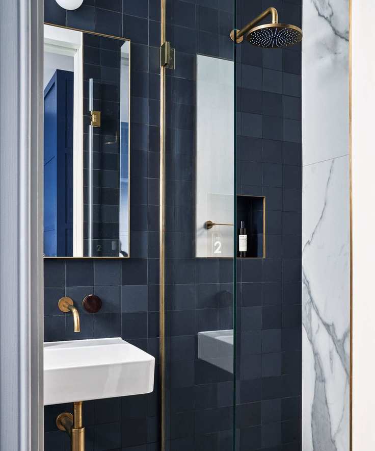 Compact bathroom featuring wall-mounted brass fixtures against a blue backdrop.