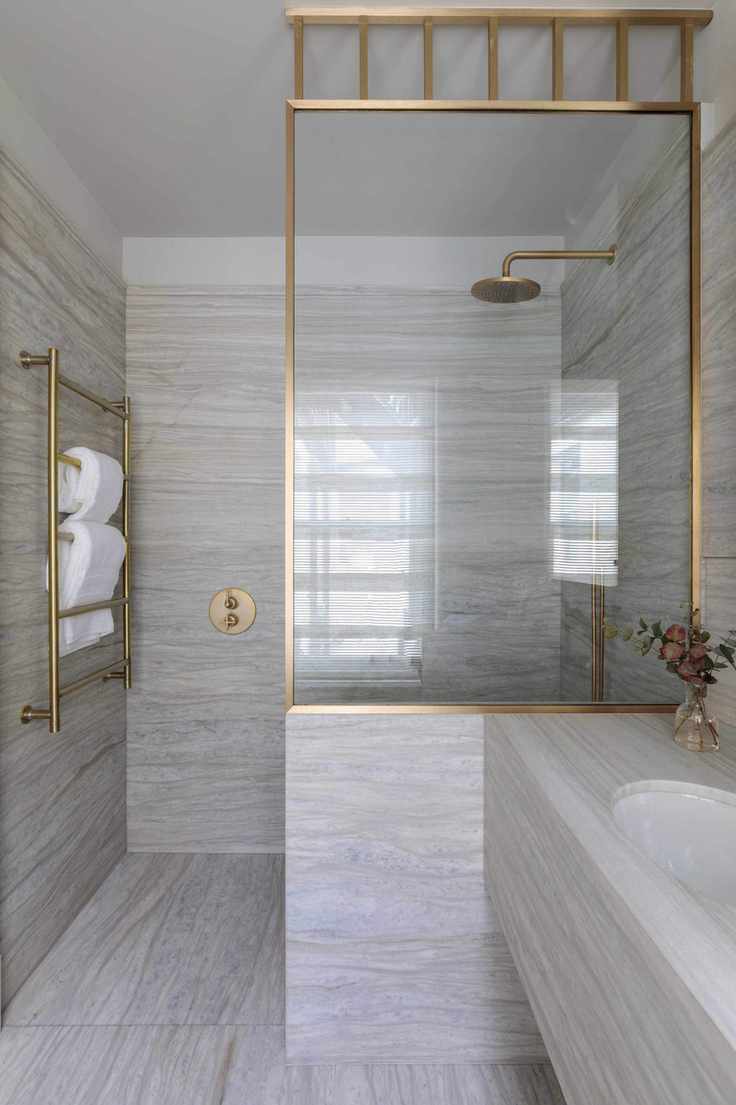 spa bathroom with neutral coloured stone floor and wall tiles and gold fixtures and fittings